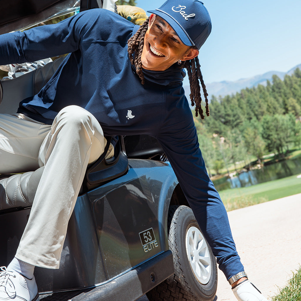 Person sitting on a golf cart with mountains and trees in the background